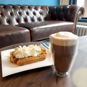 Un latte, une gaufre chantilly coin cosy avec canapé du café